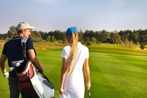 Sportive couple playing golf on a golf course walking to the nex — Stock Photo, Image