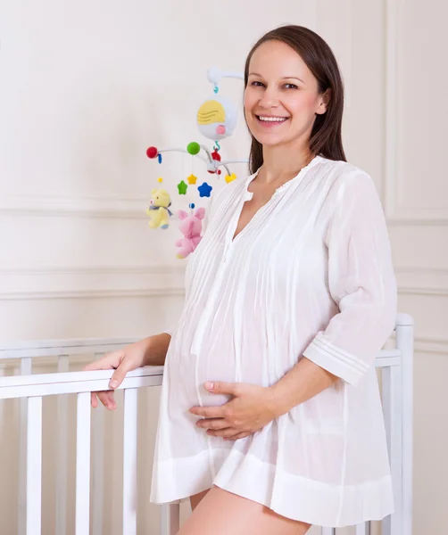 Sorridente donna incinta nella stanza dei bambini — Foto Stock