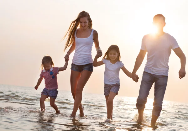 Glad ung familj ha kul kör på stranden vid solnedgången — Stockfoto