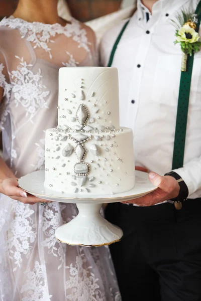 Casal alegre segurando bolo de casamento — Fotografia de Stock