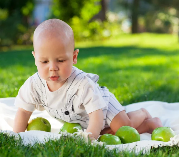 Bambino con mele verdi sull'erba verde nel parco estivo . — Foto Stock