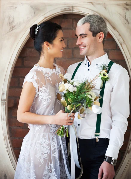 Veselá oženil pár stojící poblíž cihlová zeď — Stock fotografie