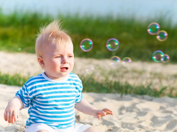 Baby on the beach playing with soap bubbles — Stock Photo, Image