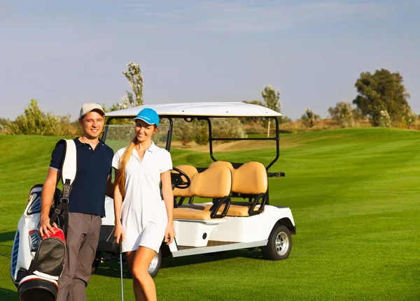 Nuori urheilullinen pari pelaa golfia golfkentällä — kuvapankkivalokuva