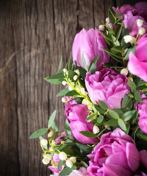 Strauß frischer rosa Tulpen und Maiglöckchen auf altem Holz — Stockfoto