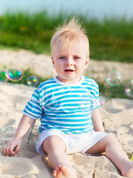 Baby on the beach playing with soap bubbles — Stock Photo, Image