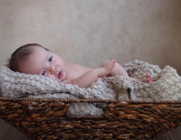 Babyjongen in de mand op de houten vloer — Stockfoto