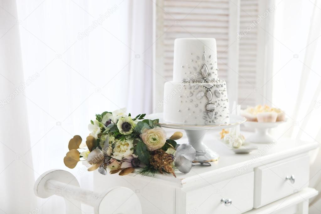 White wedding cake with silver decoration and wedding bouquet 