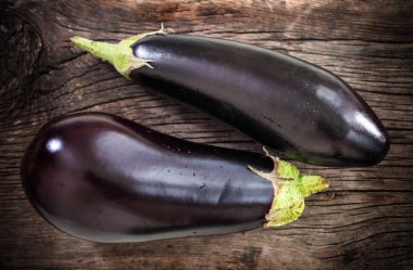 Fresh eggplants with leaves over dark background clipart