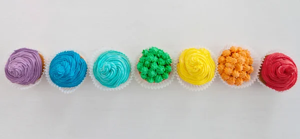 Cupcakes de arco iris en el fondo blanco con espacio de copia — Foto de Stock