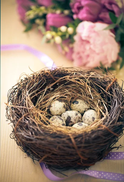 Fiori e nido pasquale con uova su sfondo rustico in legno — Foto Stock