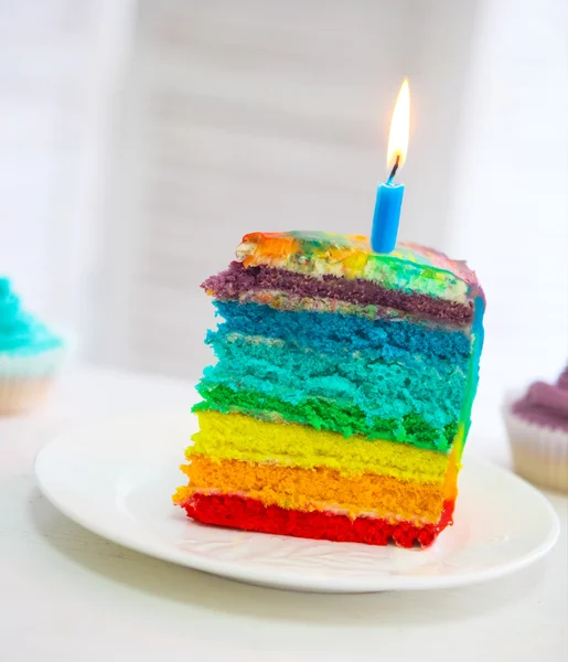 Torta arcobaleno decorata con candela di compleanno — Foto Stock