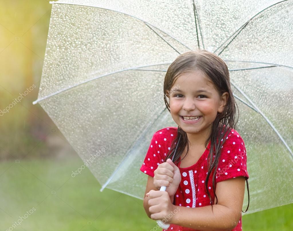 Child with wearing polka dots dress under umbrella