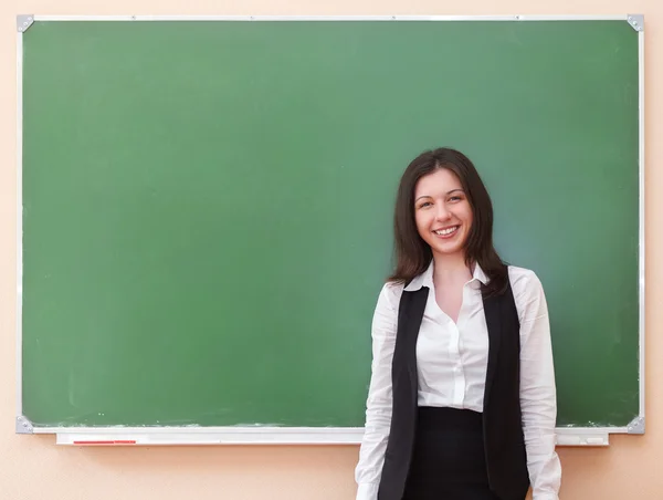 きれいな黒板近くに立っている学生の女の子 — ストック写真