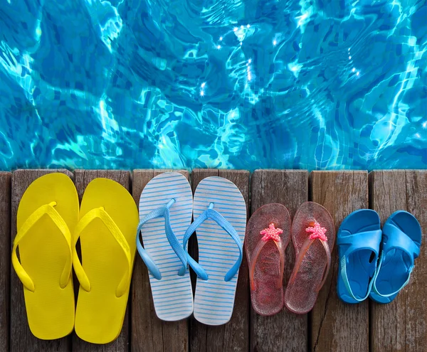 Tongs aux couleurs vives sur fond bois près de la piscine — Photo