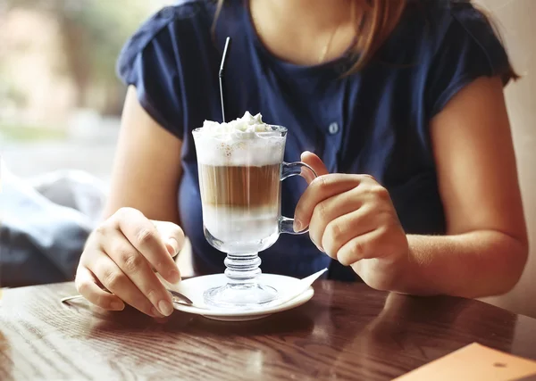 Mladá žena sedí v kavárně s šálkem kávy latte — Stock fotografie