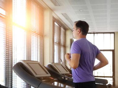 Adam bir spor merkezinde bir koşu bandı üzerinde eğitim