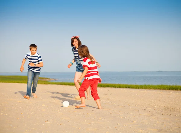 Broer en zusters spelen met een strandbal buitenshuis — Stockfoto