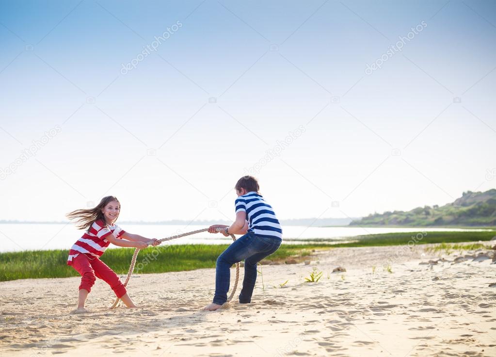 Tug of war - boy and girl playing on the beach