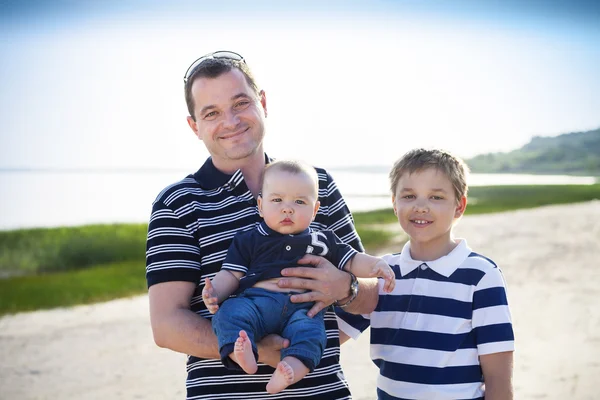 Junger Vater spielt mit kleinen Söhnen wie am Strand — Stockfoto