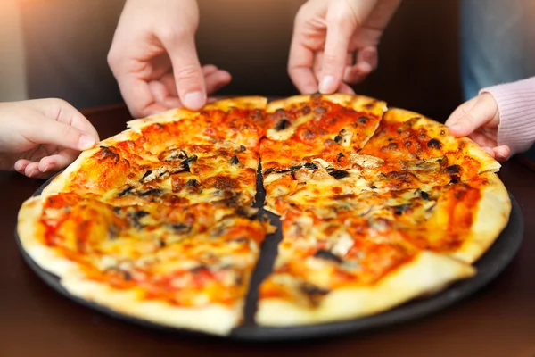 Grandes mãos de família que tomam pizza da chapa — Fotografia de Stock