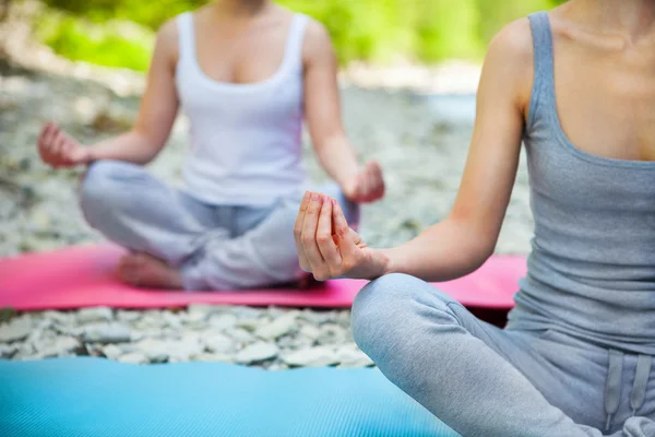 Dos mujeres practican yoga junto al río de la montaña — Foto de Stock