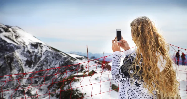 Woman photographing winter landscape mountains and snow with cel — Zdjęcie stockowe