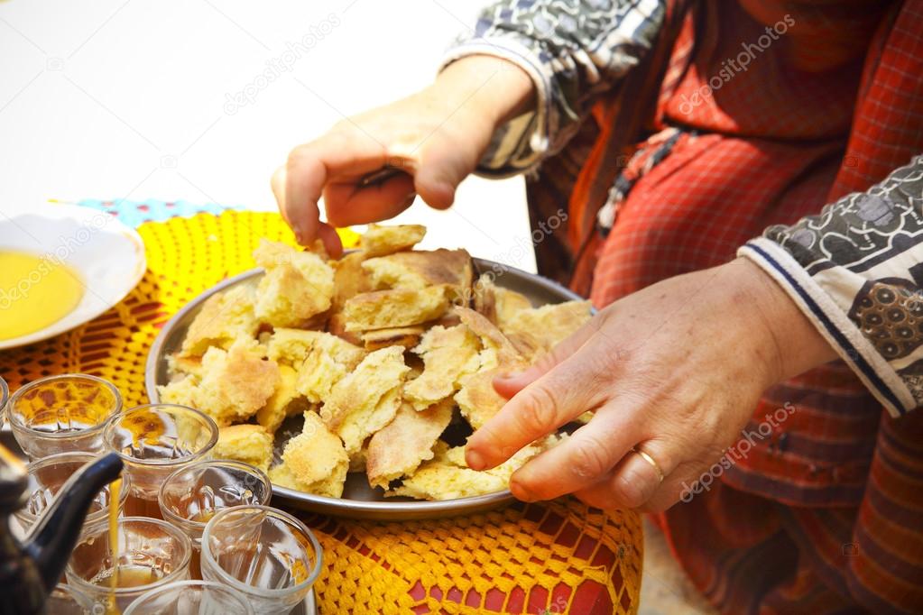 Bedouin woman wearing traditional clothing preparing bread 