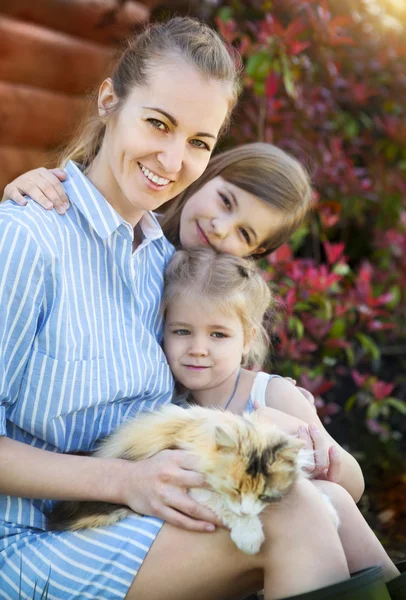 Glückliche Mutter mit ihren Töchtern, die Katze gegen die Natur halten — Stockfoto