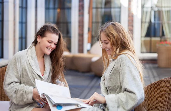 Deux jeunes femmes se relaxent dans la station thermale en lisant le magazine — Photo