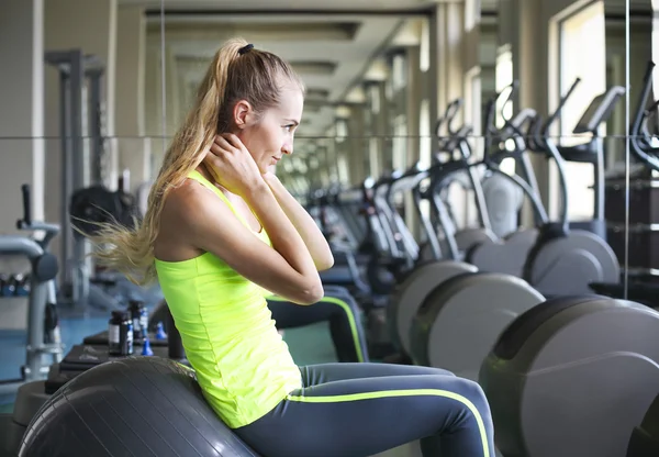 Side view of young fit woman doing sit-ups on exercise ball — Stok fotoğraf