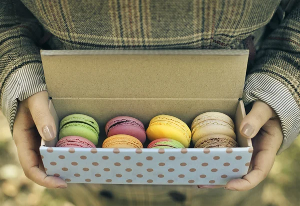 Woman holding box with colorful French macaroons in her hands — Stock Photo, Image