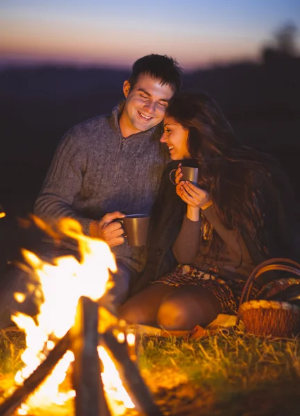 Retrato de la feliz pareja sentada junto al fuego en la playa de otoño —  Fotos de Stock