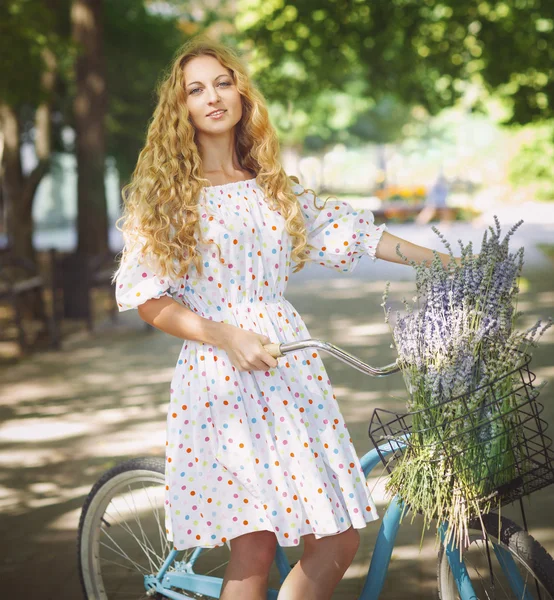 Mooi en gelukkig jonge vrouw op fiets in de zomer park — Stockfoto