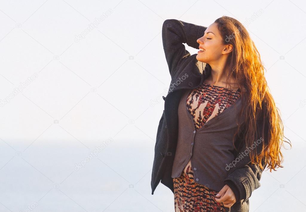 Portrait of the beautiful brunette woman at the windy autumn day