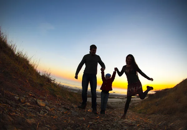 Silhouette of two happy adults and a child — Stock Photo, Image