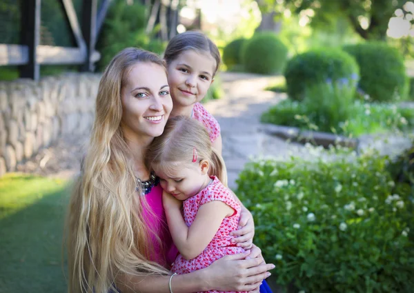 Mulher feliz e suas filhas no jardim de verão florescendo — Fotografia de Stock