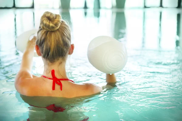 Jovem loira fazendo hidroginástica com halteres na natação — Fotografia de Stock