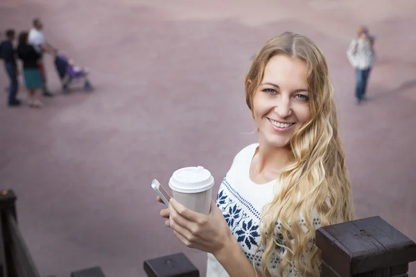 Lachende modieuze blonde vrouw met koffie buiten — Stockfoto