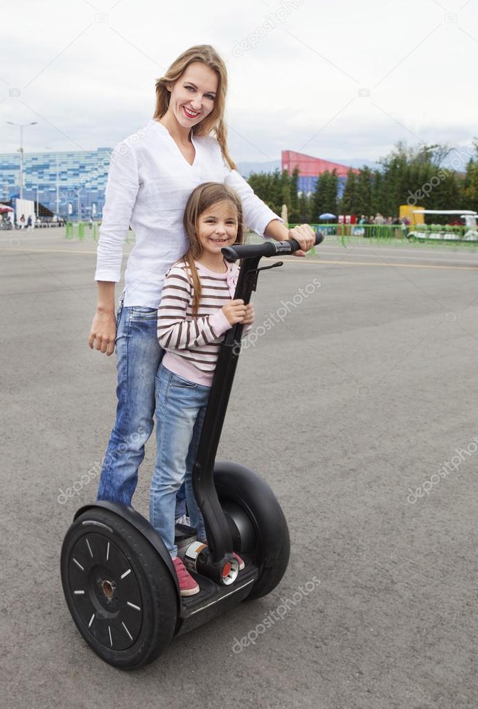 Happy young caucasian woman and her daughter on the segway