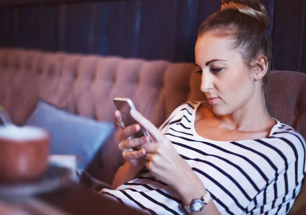 Vacker flicka med sin mobiltelefon i café — Stockfoto