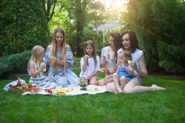 Üç mutlu genç anneler ve kızları piknik — Stok fotoğraf