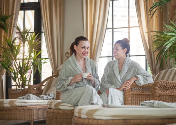 Duas jovens mulheres felizes bebendo chá no spa resort — Fotografia de Stock