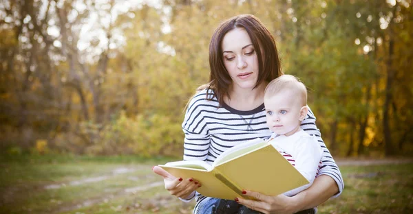 Mãe com filha ler um livro no parque — Fotografia de Stock