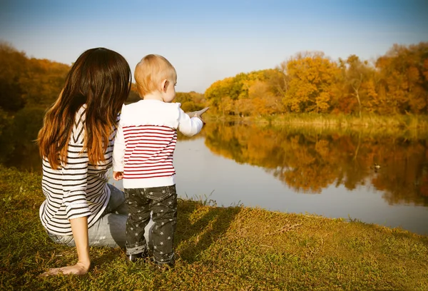Moeder en baby op herfst lake — Stockfoto