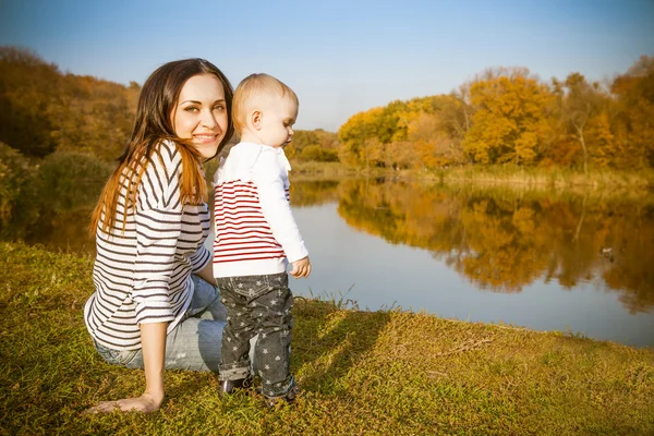 Moeder en baby op herfst meer glimlachen — Stockfoto