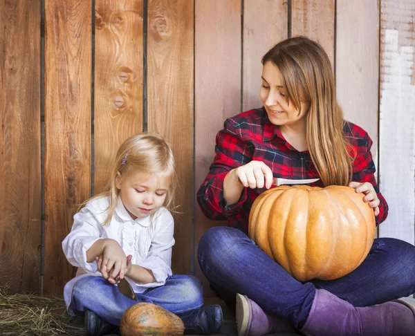 Madre y su pequeña hija tallando calabazas de Halloween — Foto de Stock