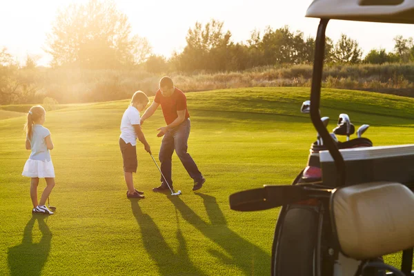 Casual kids at a golf field holding golf clubs studing with trai — Stock Photo, Image