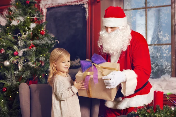 Smiling little girl with Santa Claus and gifts — Stock Photo, Image