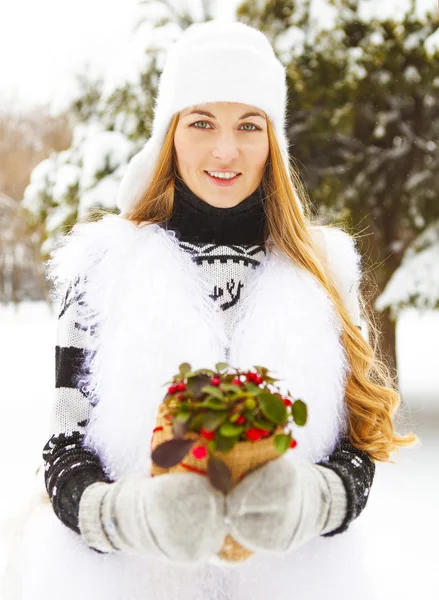 Mujer sonriente sosteniendo la planta de invierno en sus manos —  Fotos de Stock